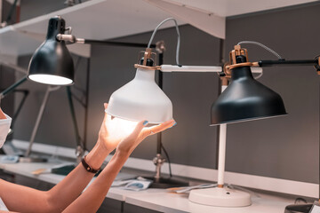 Housewife woman chooses a table lamp in the retail furniture market.