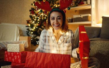 Portrait laughing looking happy woman opening Christmas gift box at home, giving presents concept