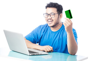 cheerful man holding credit card and smiling in front of a laptop