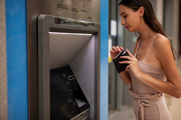 Happy woman withdrawing money from credit card. Young woman using ATM machine.