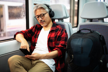 Senior man traveling by train. Man listening the music while enjoying in travel.