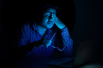 young man relaxing his eyes after using laptop at mid night