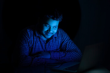 young man watching something on laptop at late night