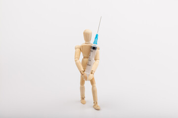 wooden mannequin with syringe against white background
