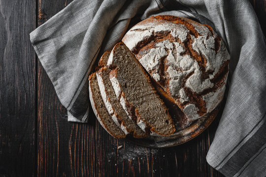 Homemade rye bread. Sliced rye bread in a round shape on a wooden background in a rustic style with towel. Top view.