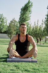 Fototapeta premium sporty man sitting on the lawn in the park training