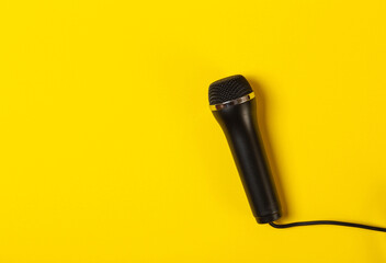 Black wired karaoke microphone on yellow background