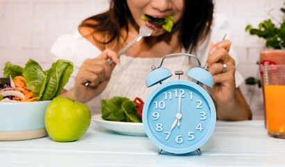 Selective focus of Blue alarm clock for diet plan and Intermittent fasting concept. 8 hours of eating period and 16 hours of fasting period