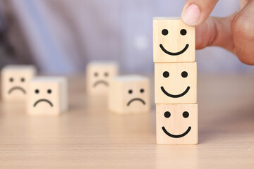 Hand holding wooden cube with smiley face icon and sad face icon. Customer Service Satisfaction Concept