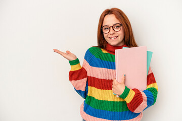 Young student caucasian woman isolated on white background showing a copy space on a palm and holding another hand on waist.