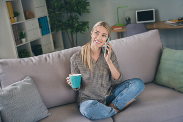 Obraz premium Photo of positive lady sit comfy divan hold latte cup listen friends holiday suggestion in living room