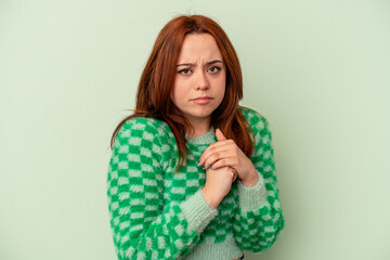 Young caucasian woman isolated on green background scared and afraid.