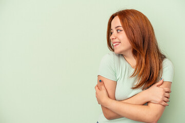 Young caucasian woman isolated on green background smiling confident with crossed arms.
