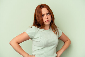 Fototapeta premium Young caucasian woman isolated on green background frowning face in displeasure, keeps arms folded.