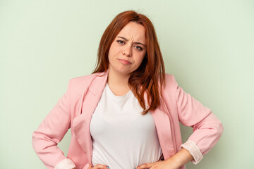 Young caucasian woman isolated on green background sad, serious face, feeling miserable and...