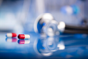 Medicine concept. Pils, shethoscope, glass tubes and beakers on blue background.
