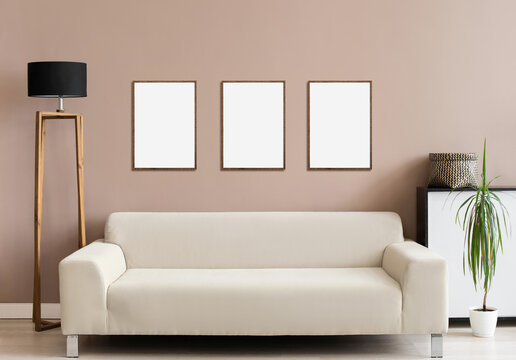 Blank picture frame mockup on gray wall. Modern living room design. View of modern minimal style interior with sofa and lamp. Three template