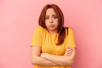 Young caucasian woman isolated on pink background blows cheeks, has tired expression. Facial...