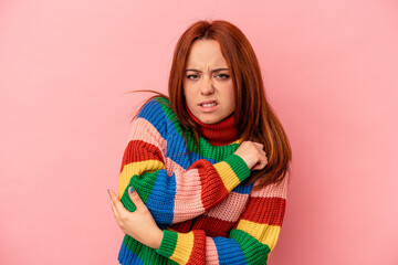 Young caucasian woman isolated on pink background massaging elbow, suffering after a bad movement.