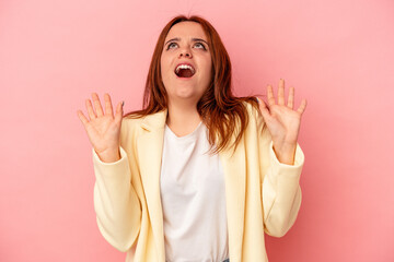 Young caucasian woman isolated on pink background screaming to the sky, looking up, frustrated.