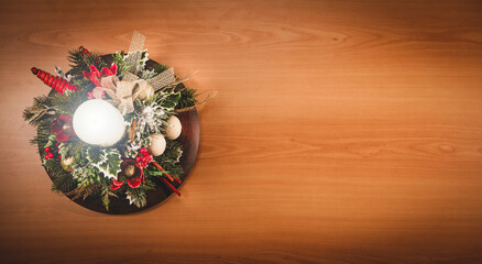 Christmas flat lay decorative composition with lighted white candle, berries, christmas balls, pine branches, leaves on wooden background with copy space
