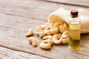 Cashew oil in glass bottle isolated on wooden table background.