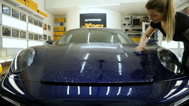 Close up to PPF installation process on a front headlight and hood. PPF is a Paint Protection Film which protect paint from scratches and stone chips. Concept of: Guard, Protect, Car, New, Work.	
