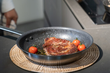 Cooked and grilled steak on pan with a little tomato with it, and take a break on a wicker plate for the next step.