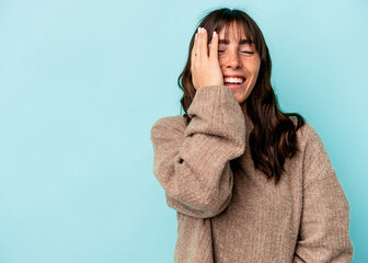 Young Argentinian woman isolated on blue background laughing happy, carefree, natural emotion.