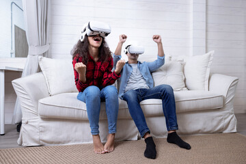 Couple wearing virtual reality glasses headsets playing VR video games in the living room together.