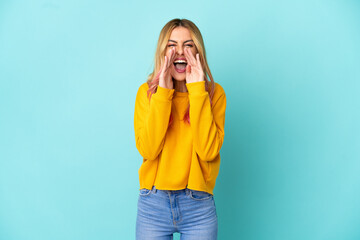 Young woman over isolated blue background shouting and announcing something