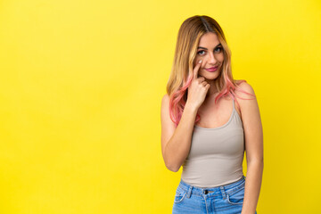 Young woman over isolated yellow background showing something