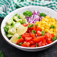 Salad with avocado, tomatoes, red onions and sweet corn in bowl. Vegetarian buddha bowl. Vegan food.
