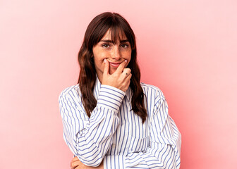 Young Argentinian woman isolated on pink background doubting between two options.