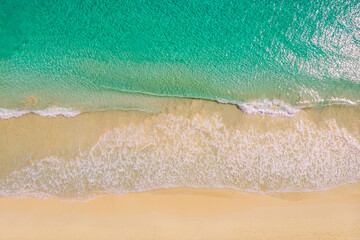 Beach and azure sea with waves from top view.