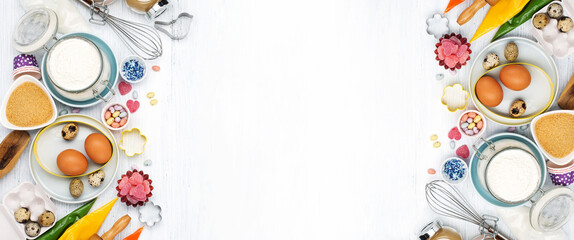 Cooking Easter background with rolling pin, eggs, whisk for whipping, cookie cutters, sugar sprinkling, flour. Rustic white wooden background, top view copy space.