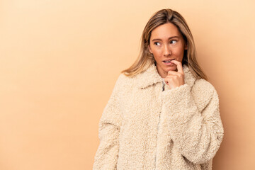 Young caucasian woman isolated on beige background relaxed thinking about something looking at a copy space.