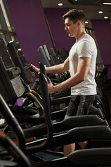 a young man is engaged in an elliptical trainer in the gym