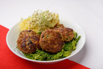 studio shot of meatballs with mashed potatoes and bean sprouts as decoration against a red and .white background