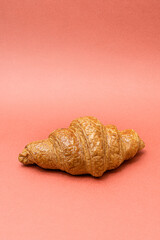 One fresh croissant on an orange background