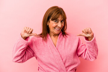Middle age caucasian woman wearing a bathrobe isolated on pink background feels proud and self...