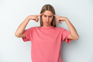 Young caucasian woman isolated on blue background focused on a task, keeping forefingers pointing head.