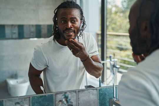 Concentrated young man examining his facial skin - Powered by Adobe