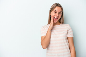 Young caucasian woman isolated on blue background shouts loud, keeps eyes opened and hands tense.