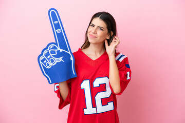 Young Italian fan woman with foam hand isolated on pink background having doubts