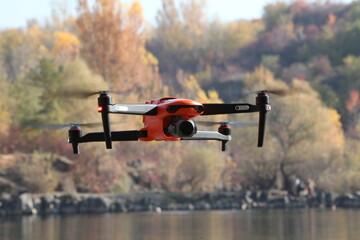 modern drone hovered in the air against the backdrop of the autumn forest