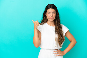 Fototapeta premium Young caucasian woman isolated on blue background unhappy and pointing to the side