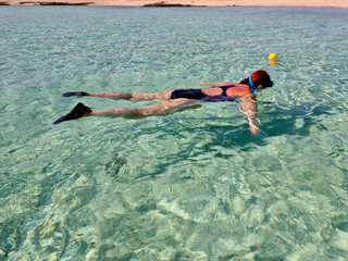 Woman swims in a transparent sea with a mask and snorkel