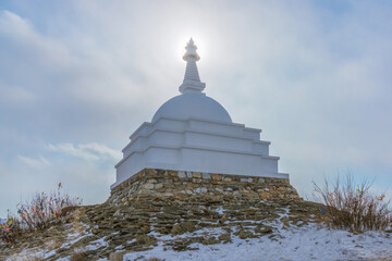 White Buddhist stupa of great enlightenment, bestowing liberation through vision on a cloudy winter day at the top of the sacred island of Ogoy. Lake Baikal, Siberia, Russia