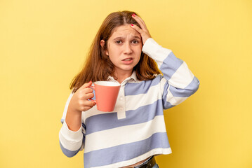 Little caucasian girl holding a pink mug isolated on yellow background being shocked, she has remembered important meeting.